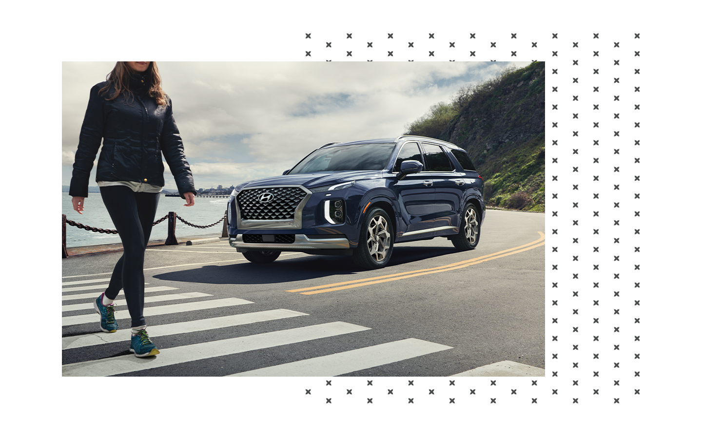 2023 Hyundai Palisade vs. 2023 Chevrolet Traverse at Haddad Hyundai | Woman crossing a cross walk while a blue 2023 Hyundai Palisade is waiting behind her