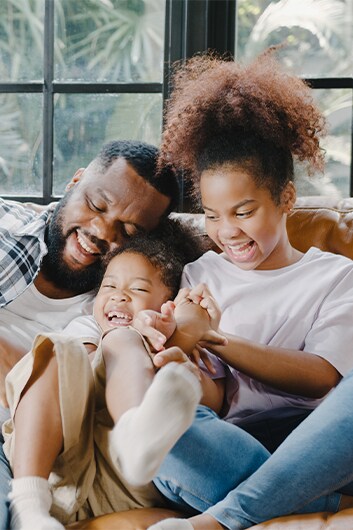 Defining GAP Insurance at Haddad Hyundai in Pittsfield, MA | Father and his two children smiling and playing around on the couch at home