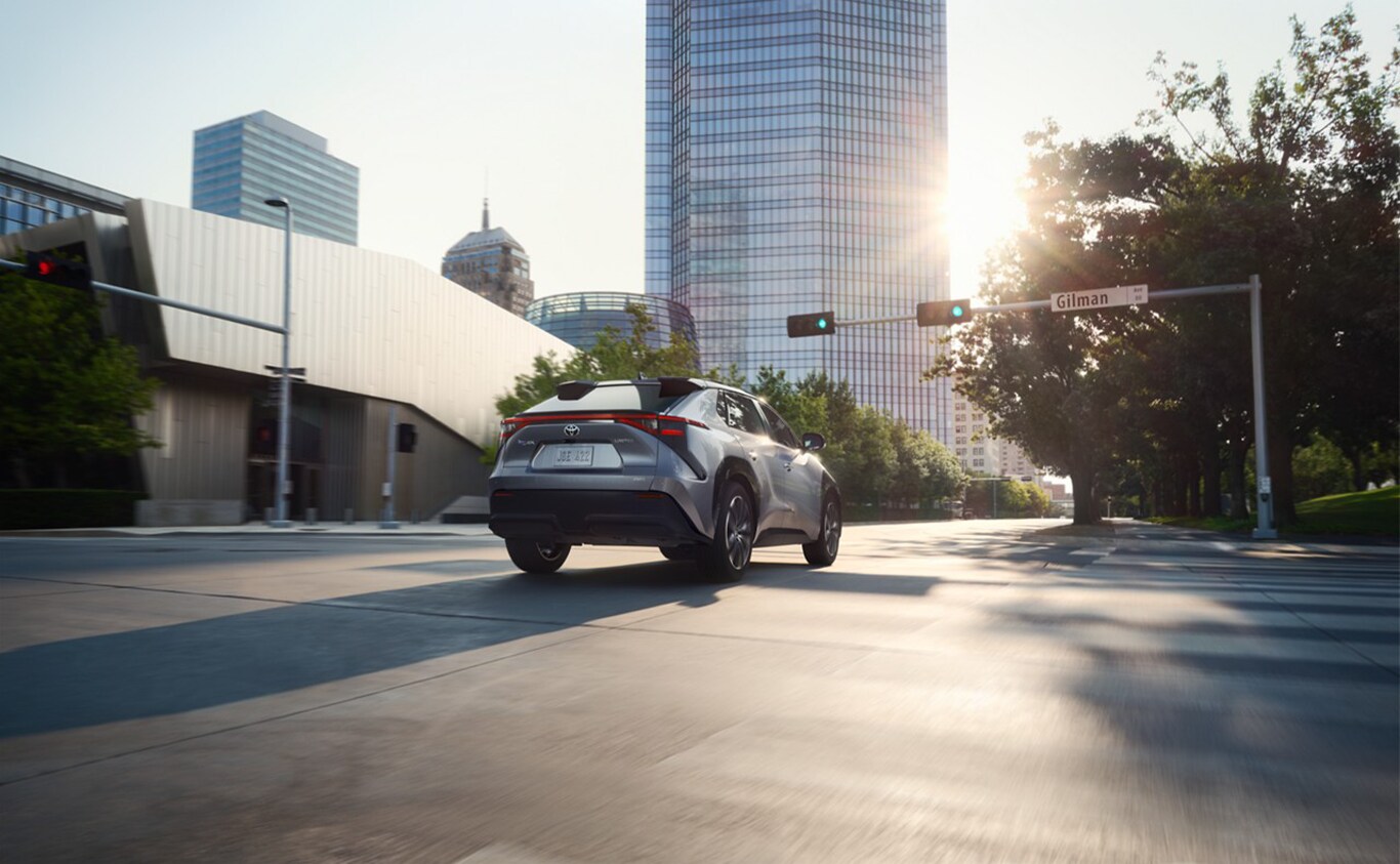 The All-New 2023 Toyota BZ4X at Haddad Toyota in Pittsfield, MA | Rear profile of a grey 2023 Toyota BZ4X driving down the street