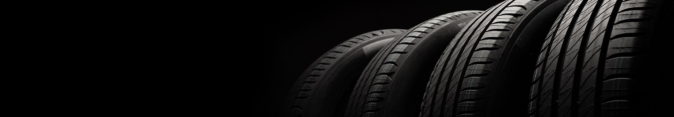 Winter Tires vs. All Season Tires at Haddad Toyota in Pittsfield, MA | Row of different tires next to each other with a black background