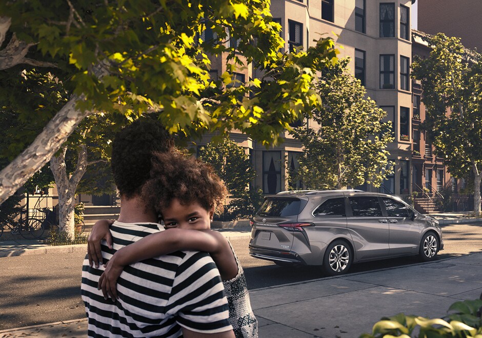 Mother holding child in front of 2022 Toyota Sienna Platinum