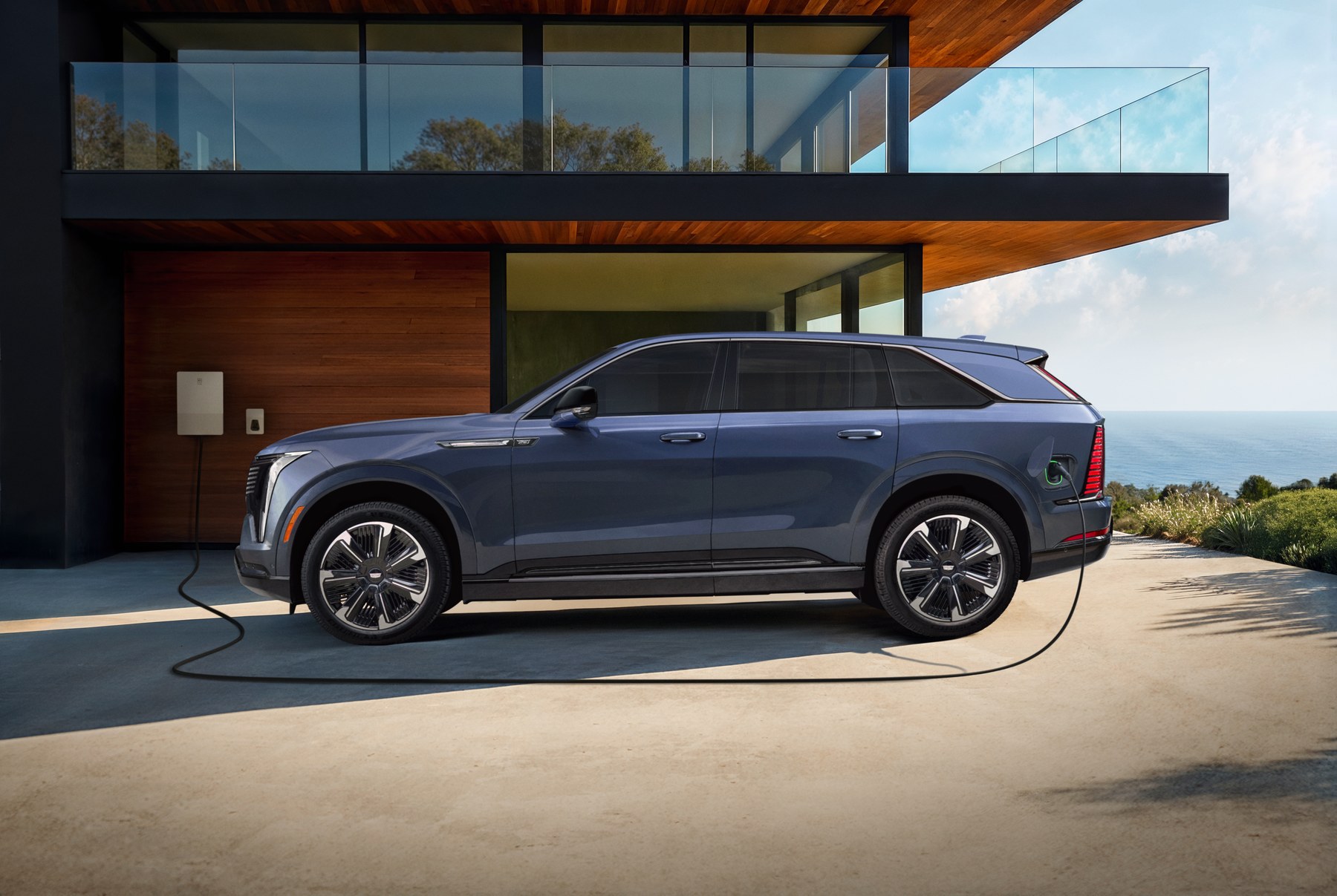 Cadillac ESCALADE IQ electric SUV shown charging at a modern home