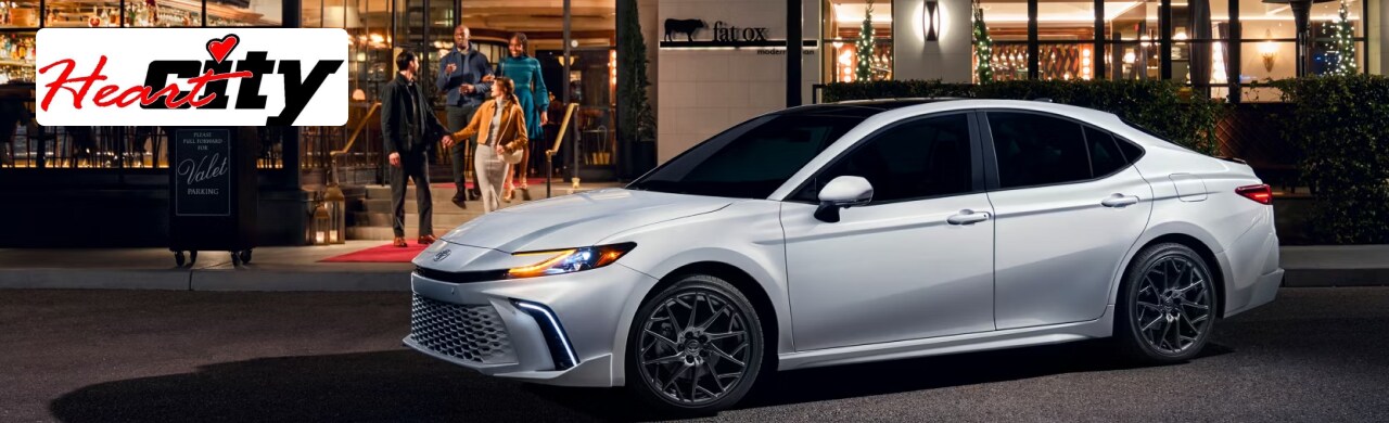 Toyota%20Camry-Hybrid-The-Perfect-Blend-of-Efficiency-and-Luxury12.png A white 2024 Toyota Camry parked in front of a restaurant at night