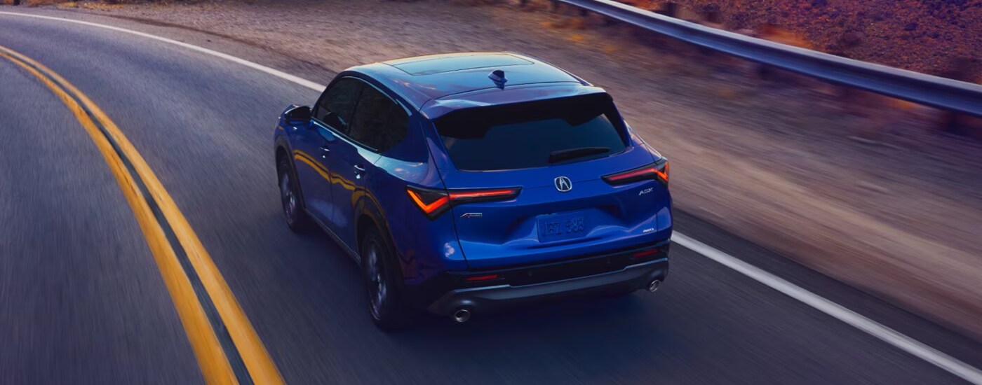2025%20Acura%20ADX%20-%20bend.png Blue 2025 Acura ADX driving along an open road