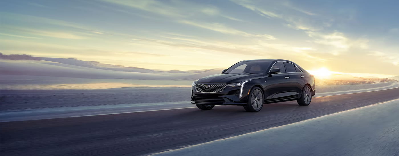 Black 2025 Cadillac CT4 driving down an open road.