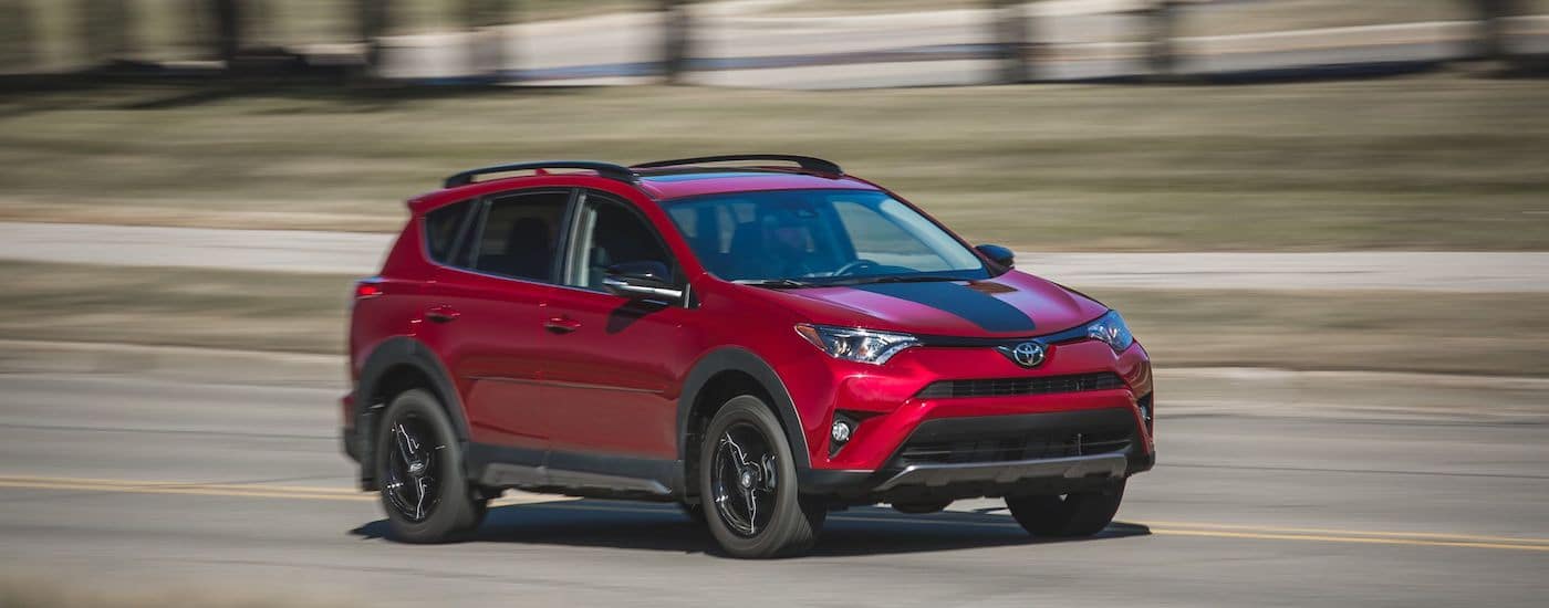 Red 2018 Toyota RAV4 driving down a street.