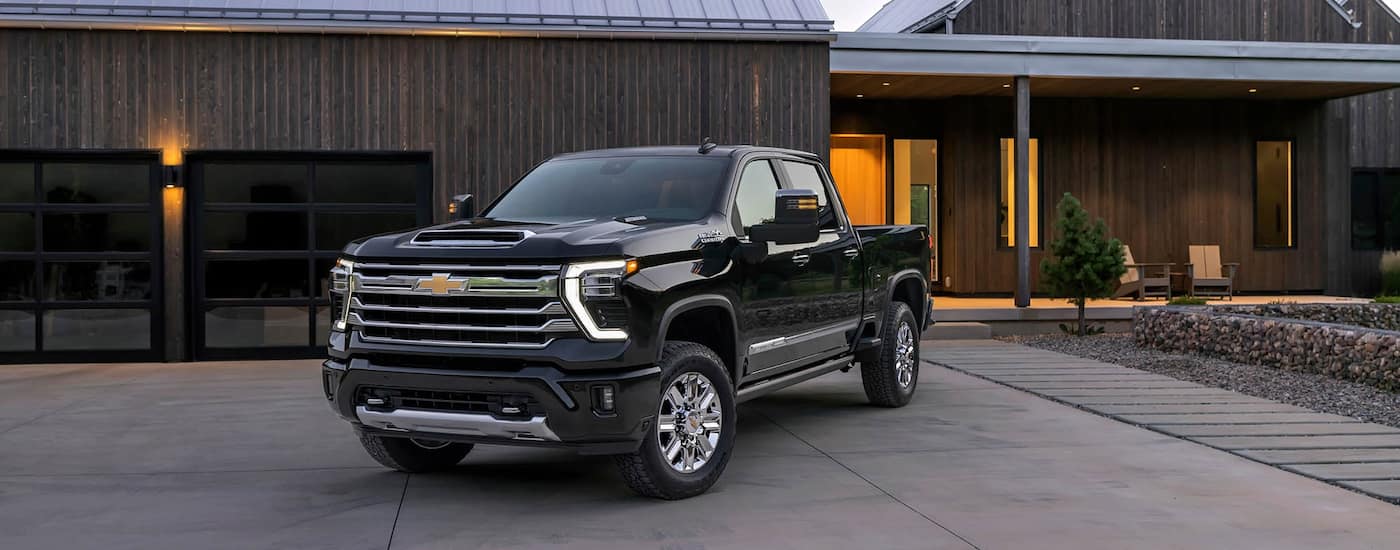 Black 2026 Chevy Silverado 2500 HD parked near garage.