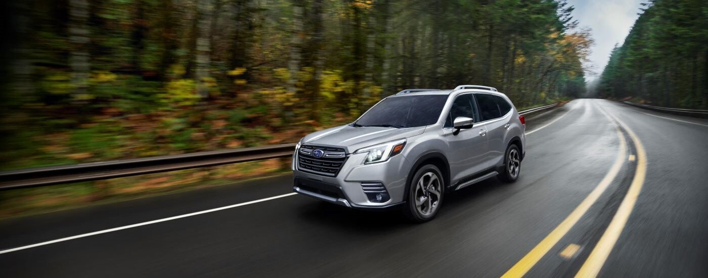 Silver 2023 Subaru Forester driving down an open road.