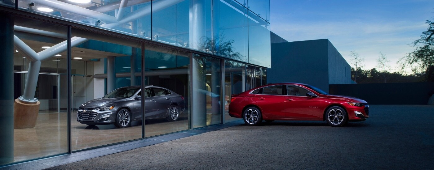 A silver and a red 2025 Chevy Malibu from the side.