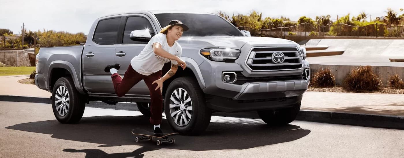 Used Vehicles for Sale Near Me - 2022 Toyota Tacoma Limited - Silver Skateboard.jpg A skateboarder is riding next to a silver 2022 Toyota Tacoma Limited.