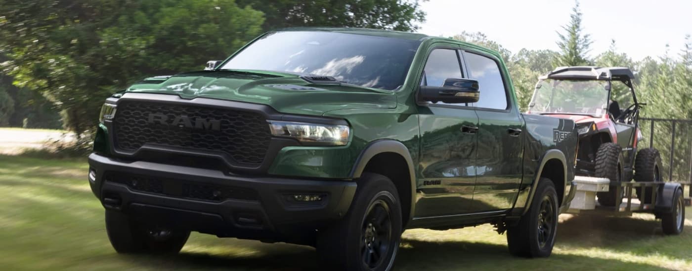 Green 2025 Ram 1500 towing an ATV.
