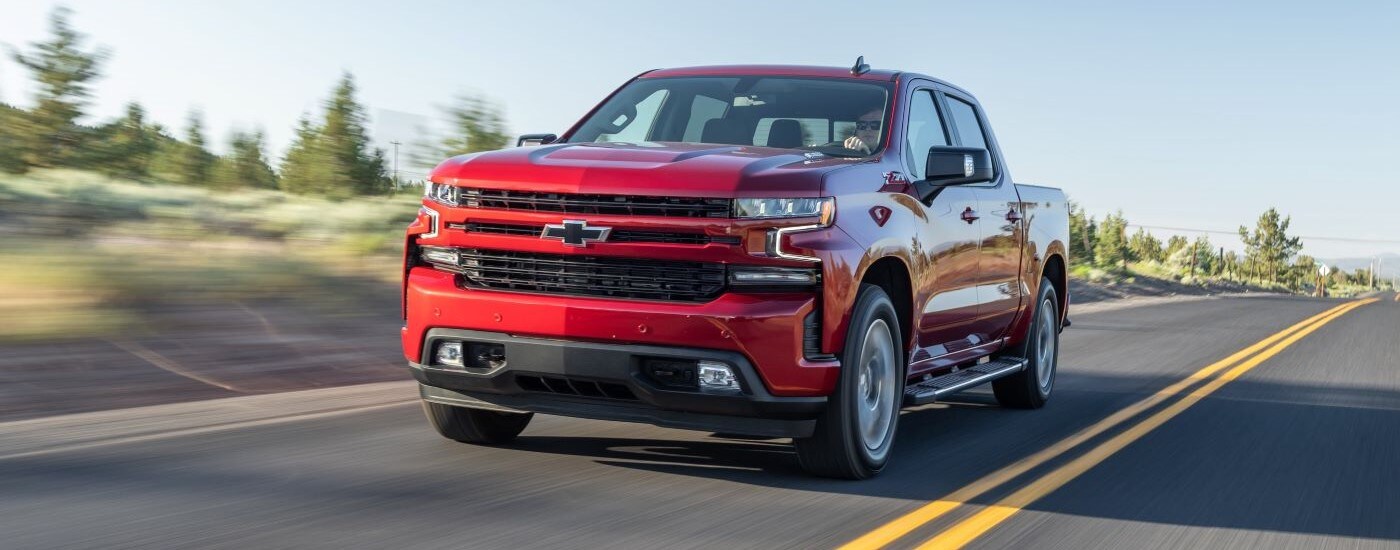 Red 2020 Chevy Silverado 1500 Z71 driving down a dealer with trucks for sale near Durham.