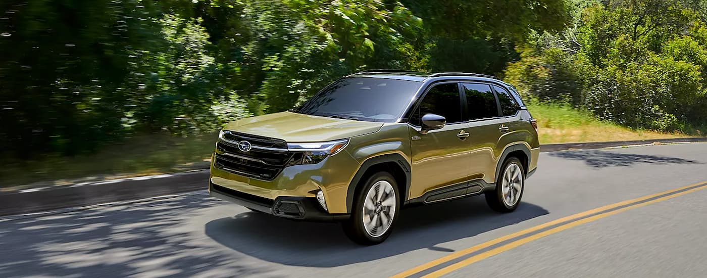 Yellow 2025 Subaru Forester driving down an open road.