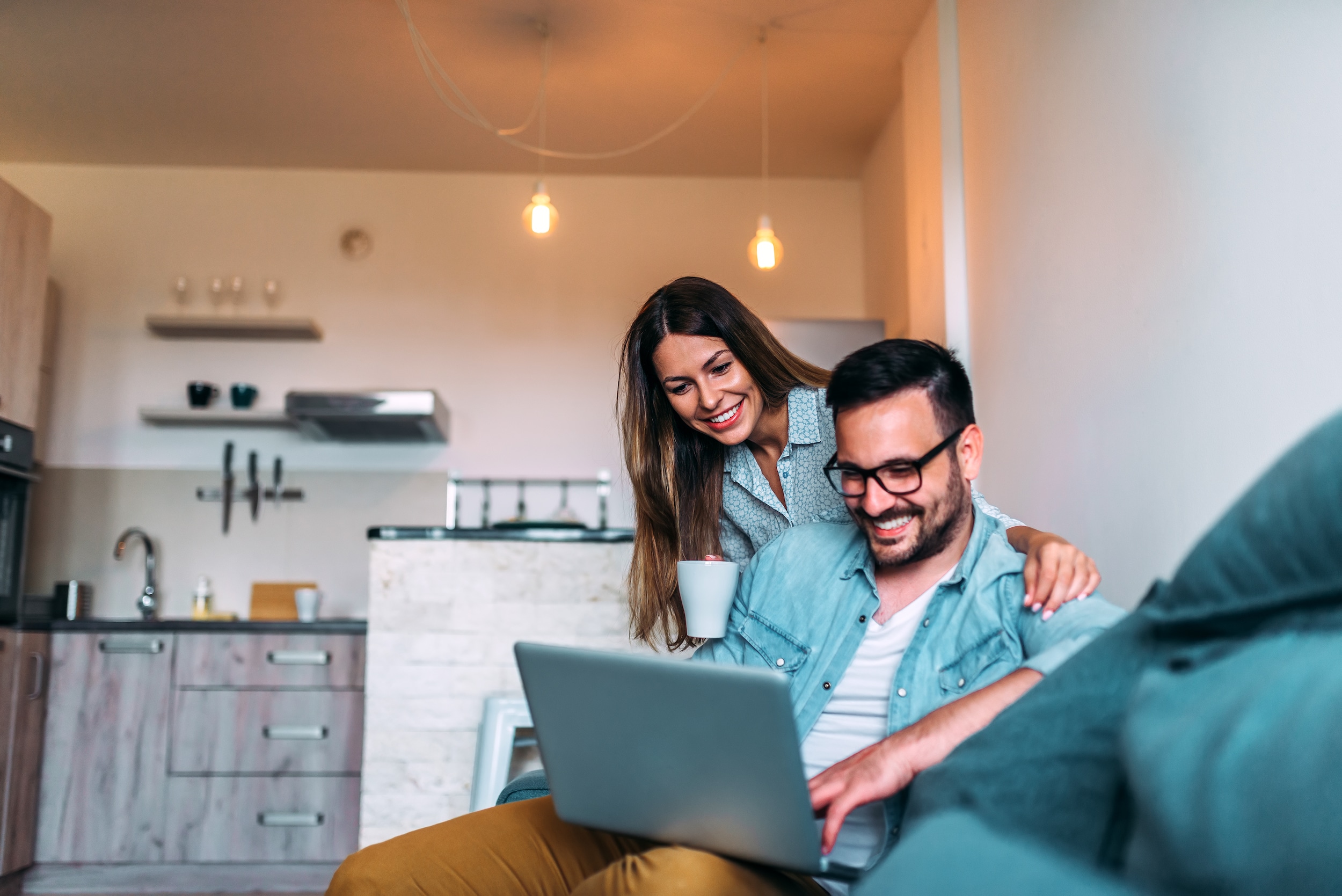 Young couple using a laptop while sitting on the sofa at home.jpg