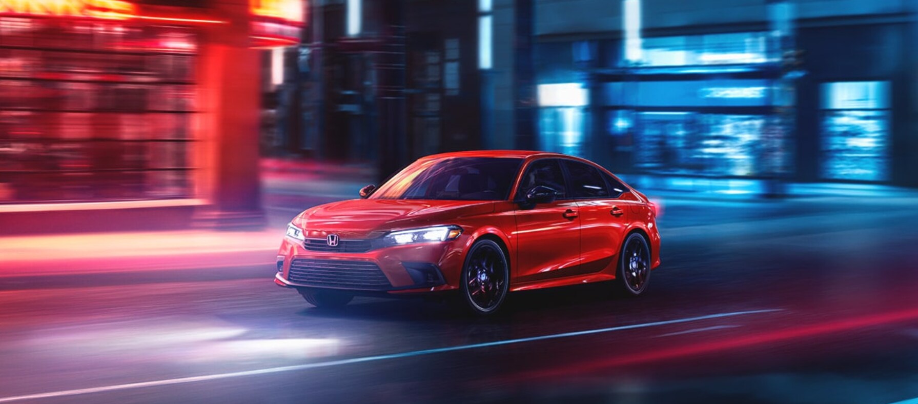 2023-honda-civic-1.PNG A red 2023 Honda Civic drives down a city street at night