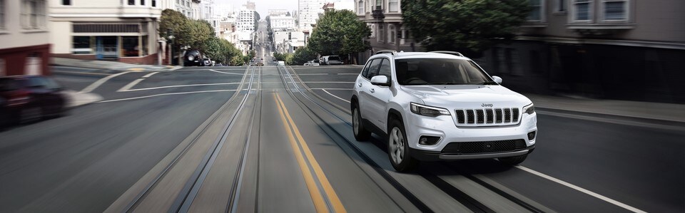 White Jeep Cherokee front view driving in city