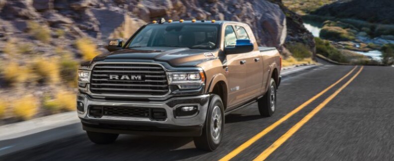 Brown RAM 2500 driving on highway front driver side view