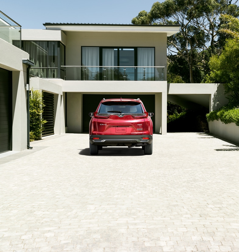 2022-Honda-CR-VHybrid-Touring-SUV.png red Honda CR-V SUV rear hatch shown, parked in front of a modern home