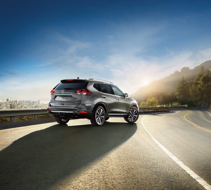 2020-Nissan-Rogue-SL-AWD-SUV-L05 (3).png dark grey Nissan Rogue SUV driving on an empty road