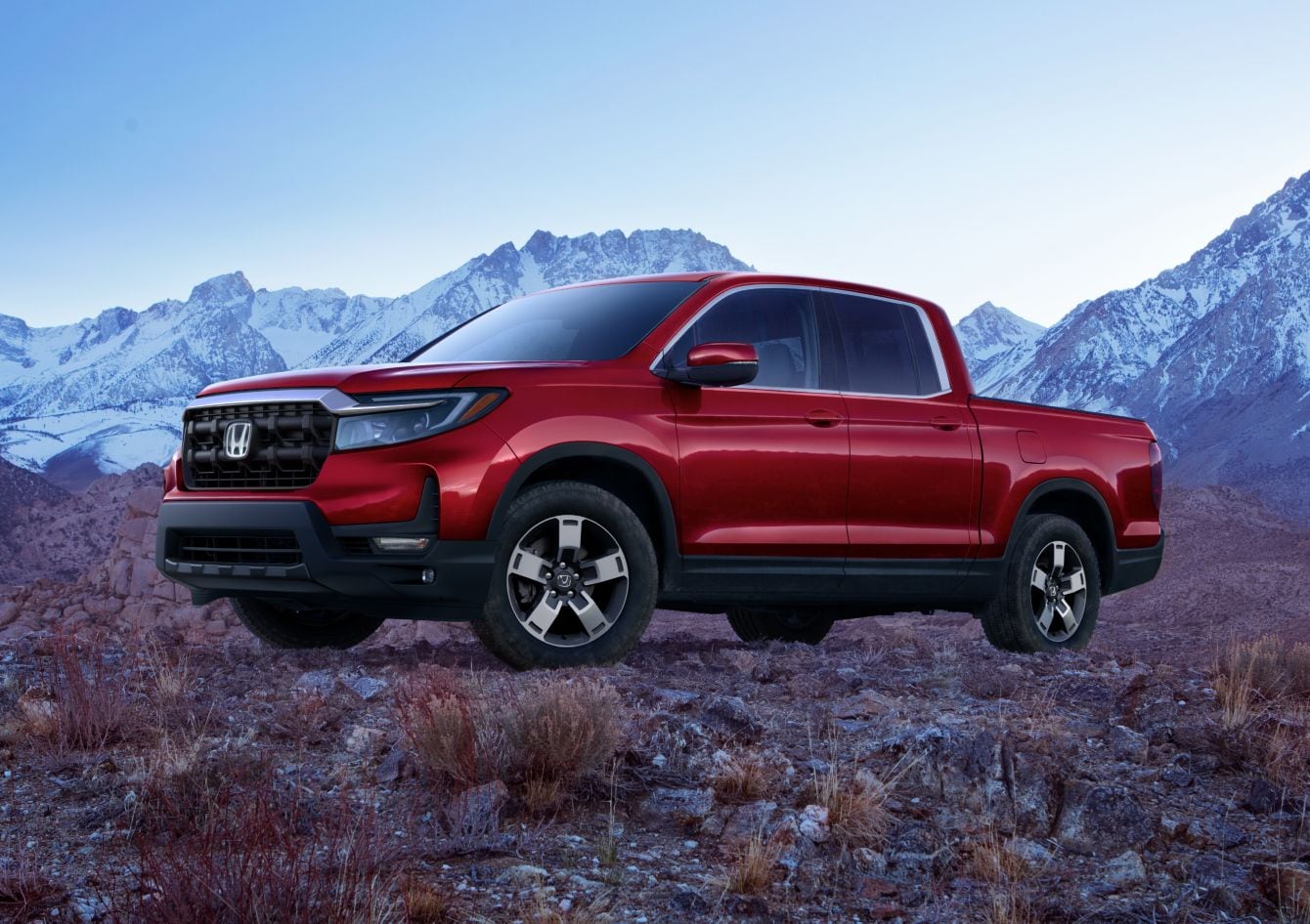 red Honda Ridgeline parked on rocks and scrub brush