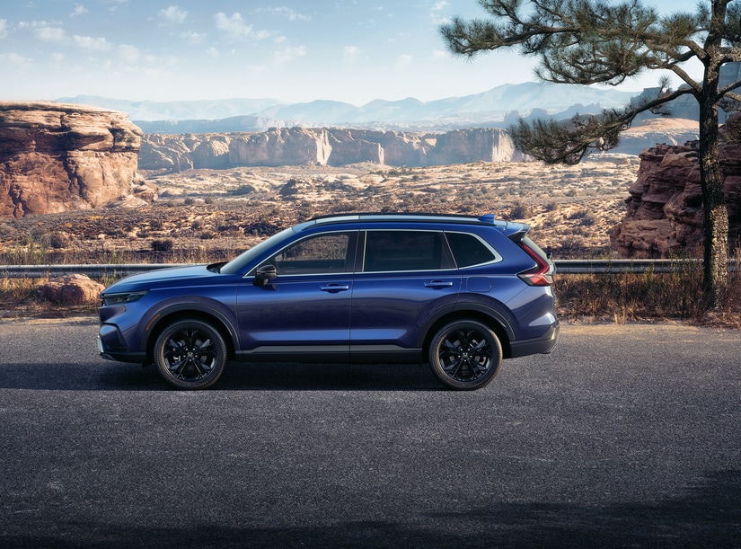 2024-Honda-CRVHybrid-SportTouring-SUV-L0.png blue Honda CR-V Hybrid parked at a turnoff overlooking a desert valley
