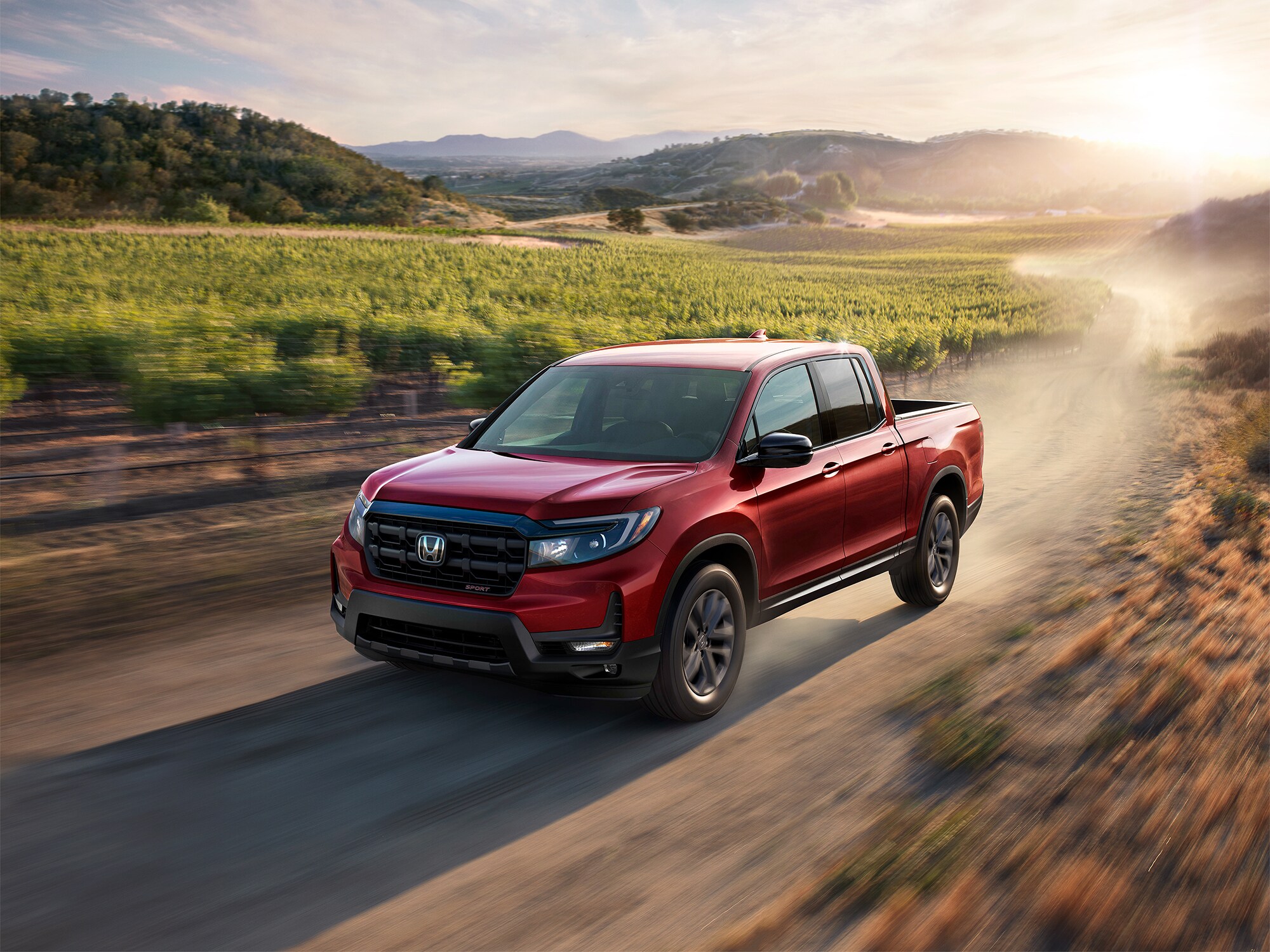 red Honda Ridgeline driving fast through a dry vineyard area