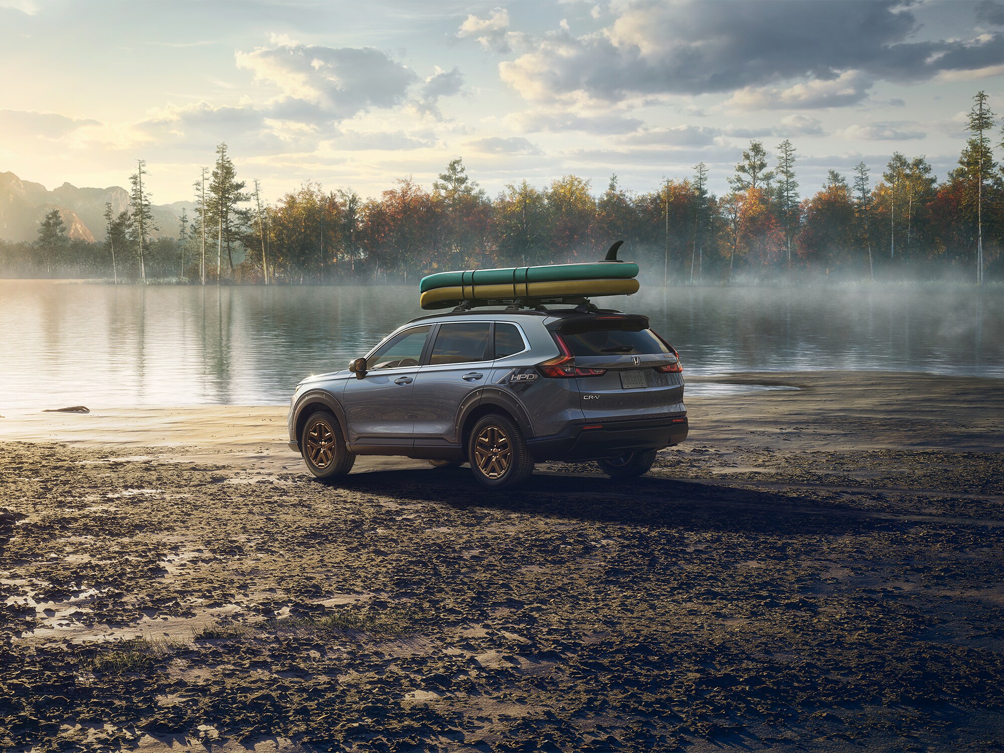 silver new Honda CR-V parked at a lake with paddleboards on the roof rack