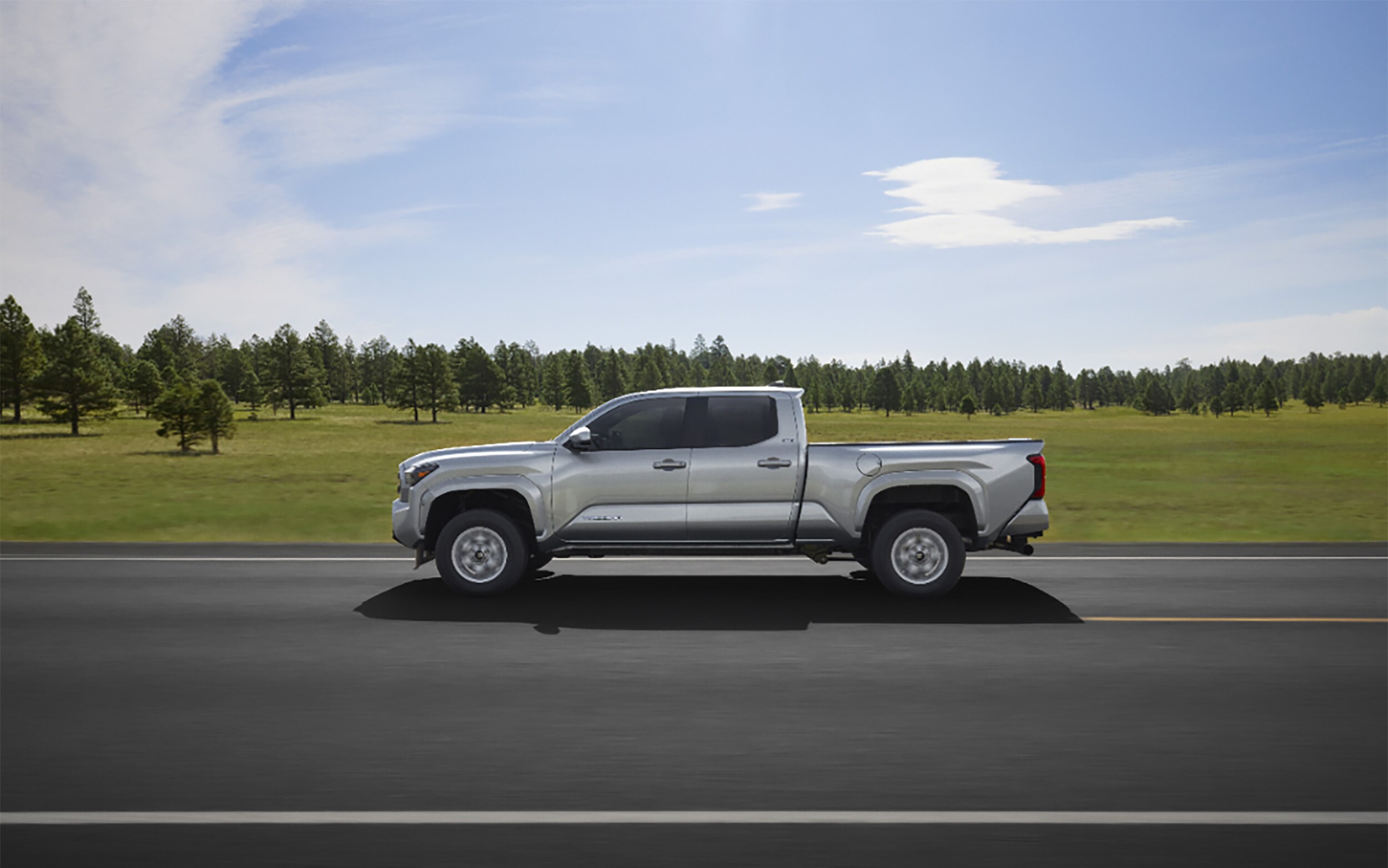 silver Toyota Tacoma driving on newly paved road