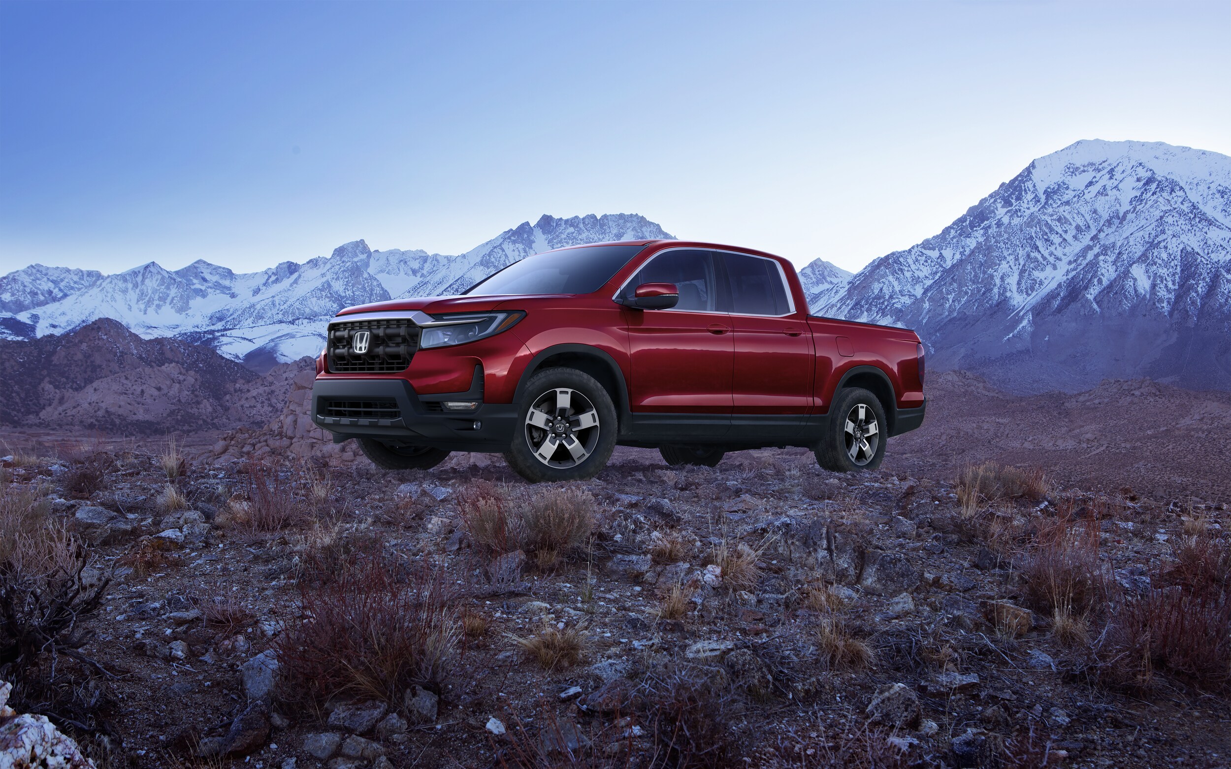 red Honda Ridgeline parked on a rocky ridge at dusk