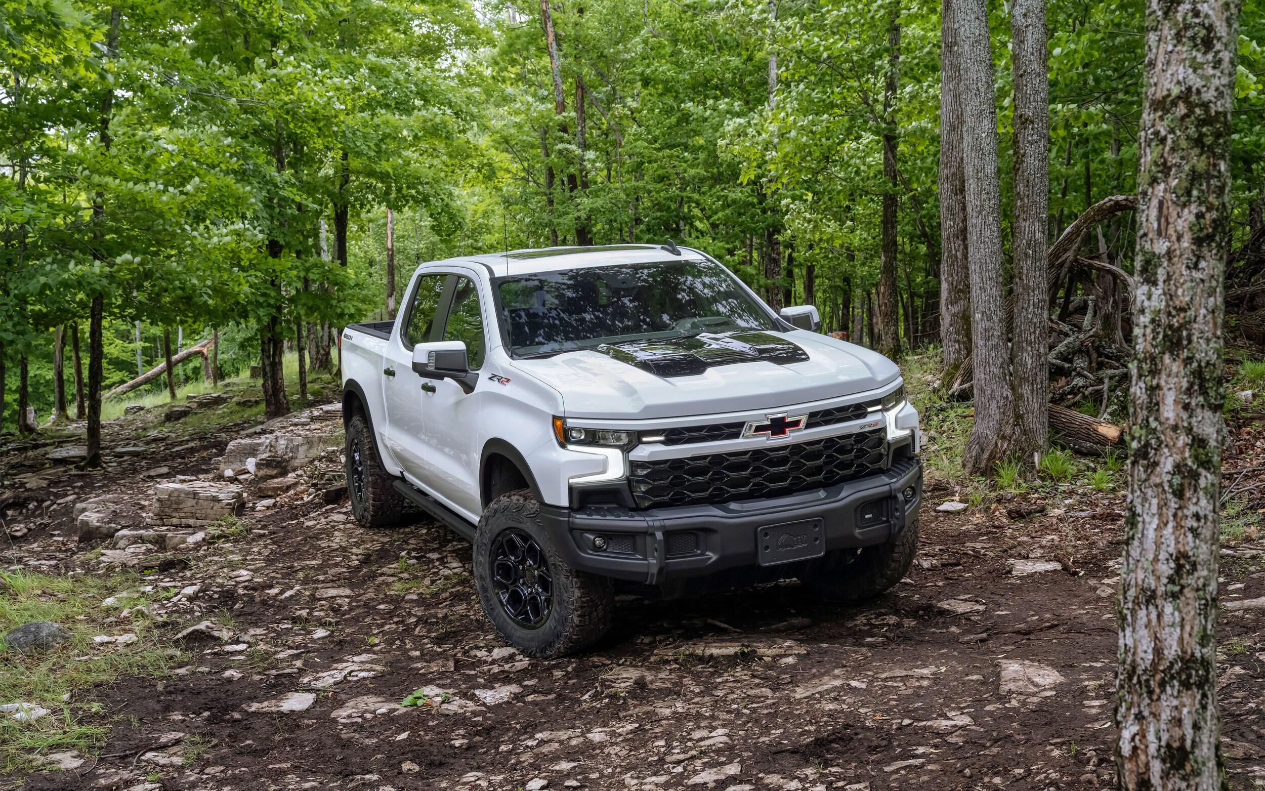 white Chevy Silverado truck parked in a clearing in a wooded area