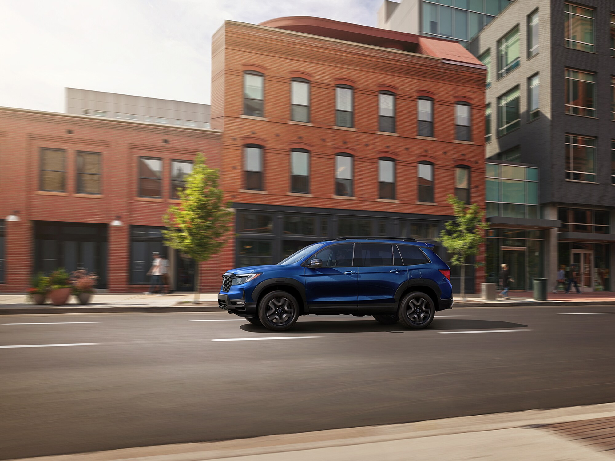 blue Honda Passport driving through a downtown area with brick buildings