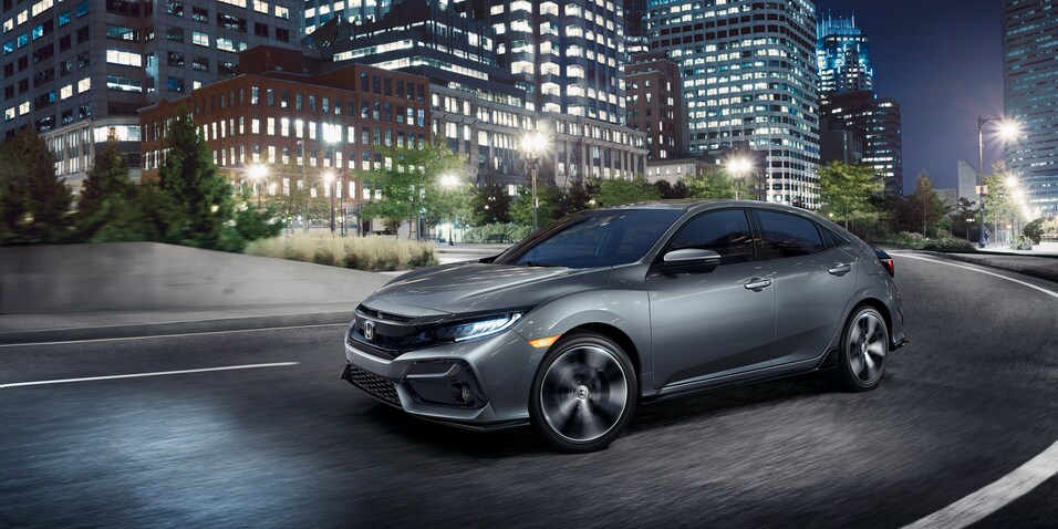 2021-Honda-Civic-SportTouring-Hatchback-L01 (2).png silver Honda Civic Hatchback driving through a lit city at night