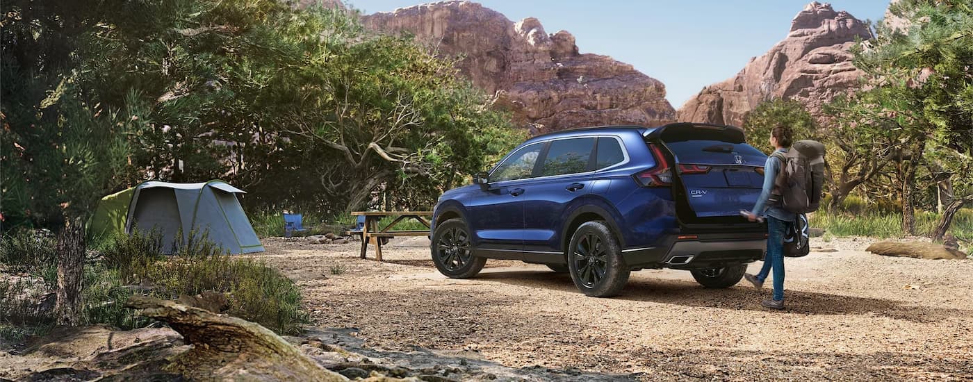 Honda%20CR-V%20for%20Sale%20-%202024%20Honda%20CR-V%20Sport%20Touring%20Hybrid%20-%20Blue%20Hiking.jpg A blue 2024 Honda CR-V Sport Touring Hybrid is parked at a hiking trail.