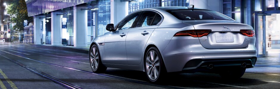 SILVER 2020 JAGUAR XE DRIVING DOWN ROAD IN CITY.