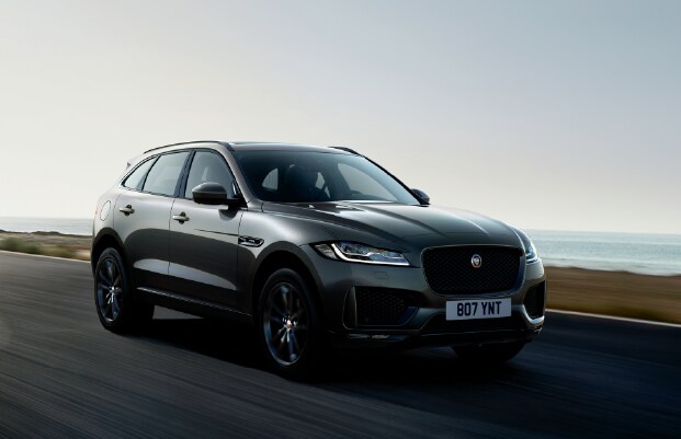 2020 JAGUAR F-PACE DRIVING DOWN ROAD NEAR LAKE. IMAGE SHOWS BLACK F-PACE.
