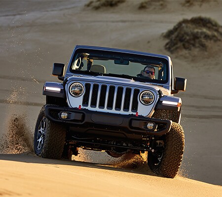 Silver Jeep Wrangler Driving on Sand