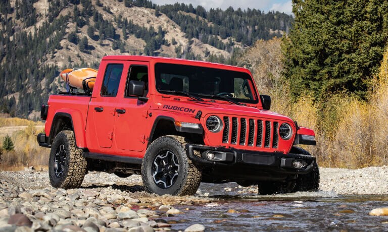 2022 Jeep Gladiator driving in a stream with kayaks