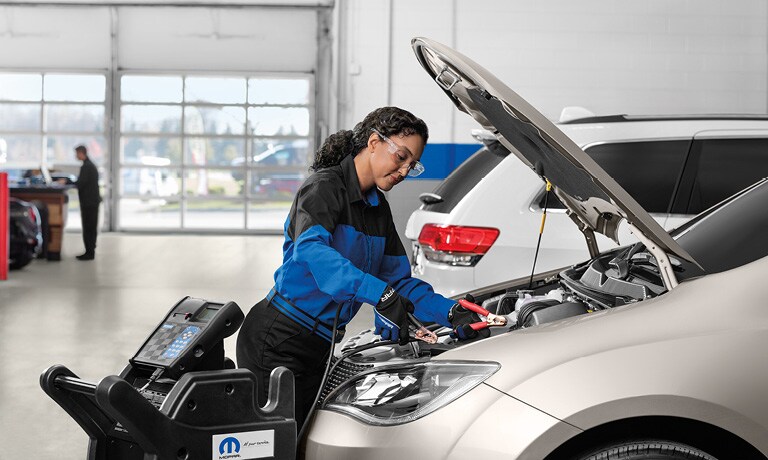 Technician checking battery under hood