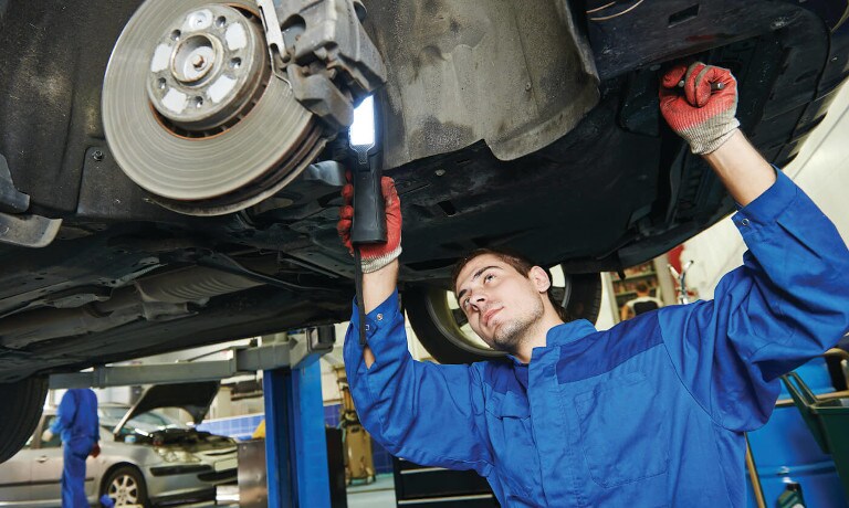 Technician with a light underneath a car