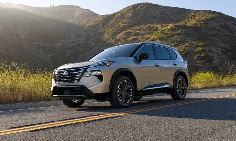 2026 Nissan Rogue driving by grassy hills