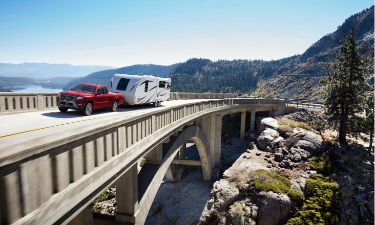 2025 Nissan Frontier towing a camper on bridge