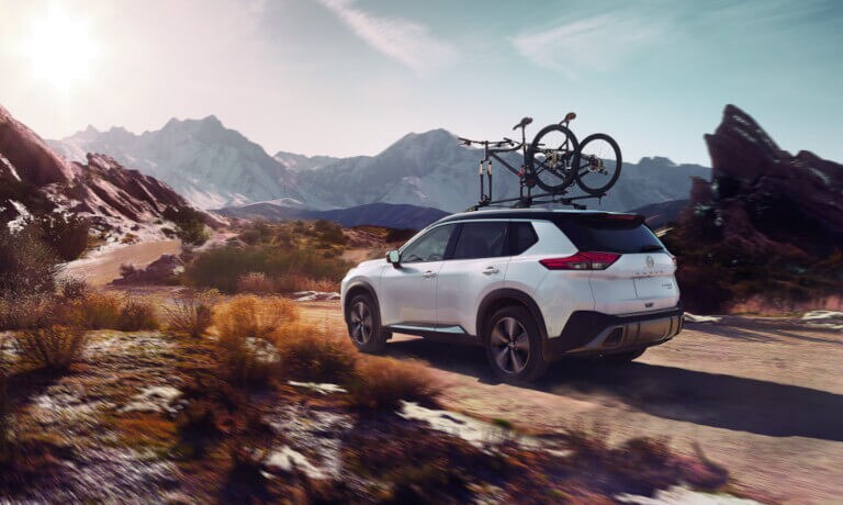 2023 Nissan Rogue driving in desert with bikes on top