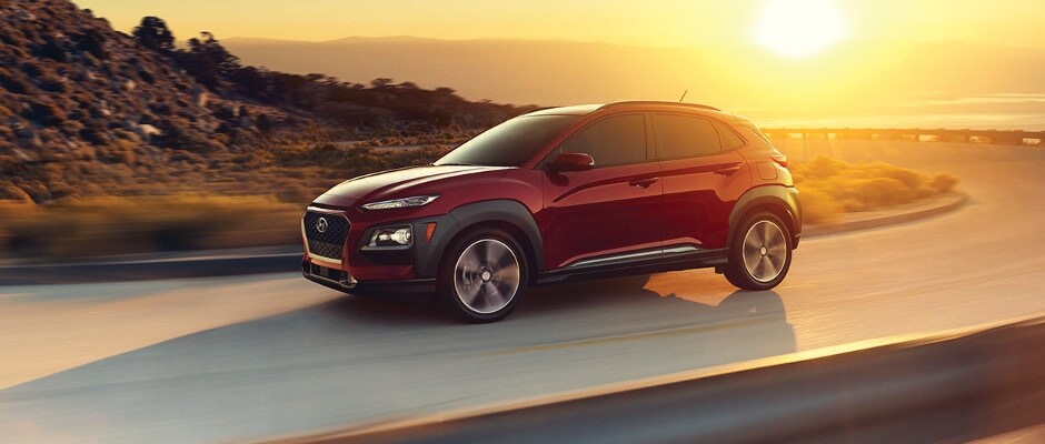 Schedule a Test Drive A red Hyundai Kona driving on a highway at sunset