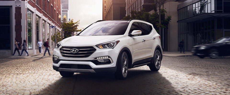 A white Hyundai Santa Fe parked in a city A white 2018 Hyundai Santa Fe parked on a cobblestone street in the middle of the city