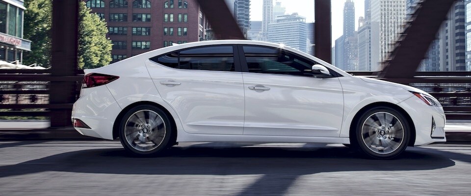 2019 Hyundai Elantra Exterior side shot of a white 2019 Hyundai Elantra driving downtown