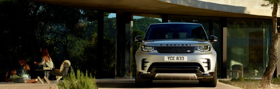 2020 GRAY LAND ROVER DISCOVERY PARKED IN FRONT OF HOME UNDER OVERHANG.png