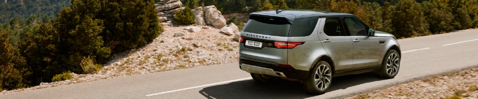 2020 GRAY LAND ROVER DISCOVERY DRIVING DOWN ROAD IN MOUNTAINS.png