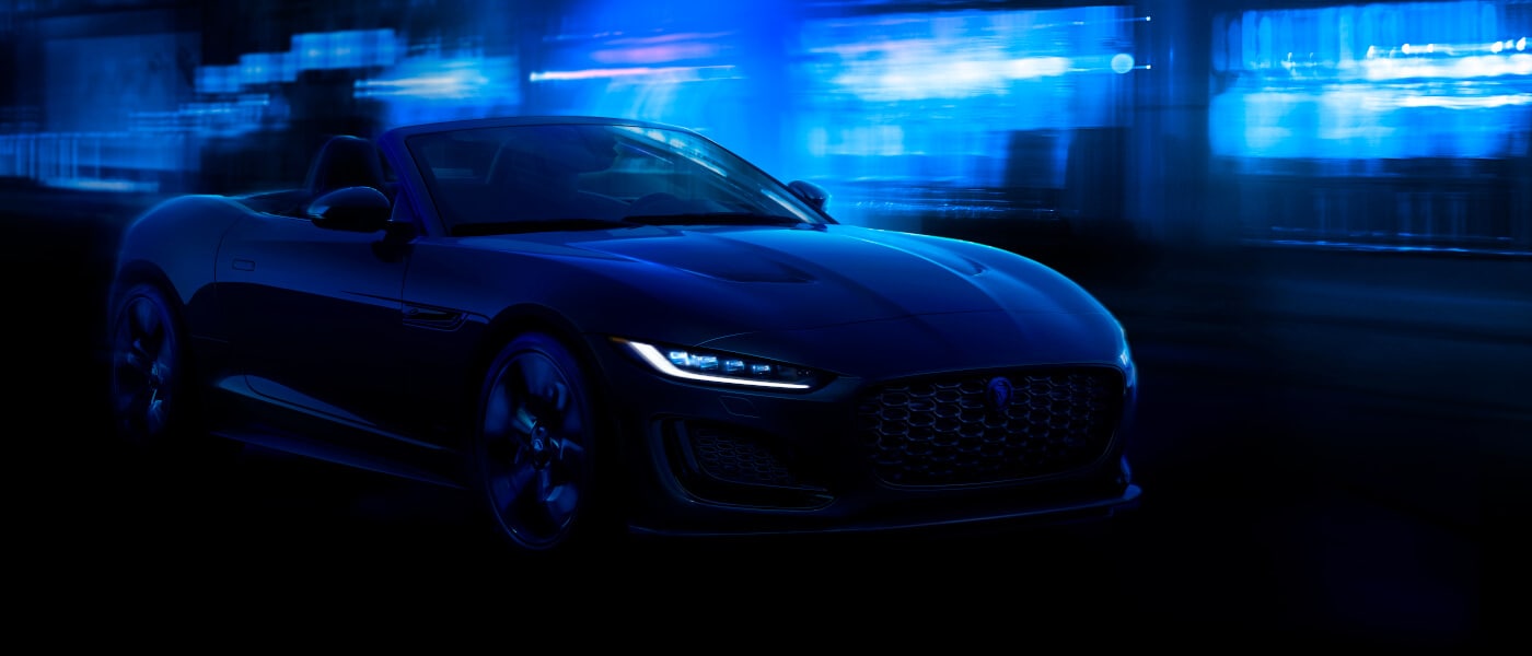 2024 Jaguar F-TYPE driving by lit blue building