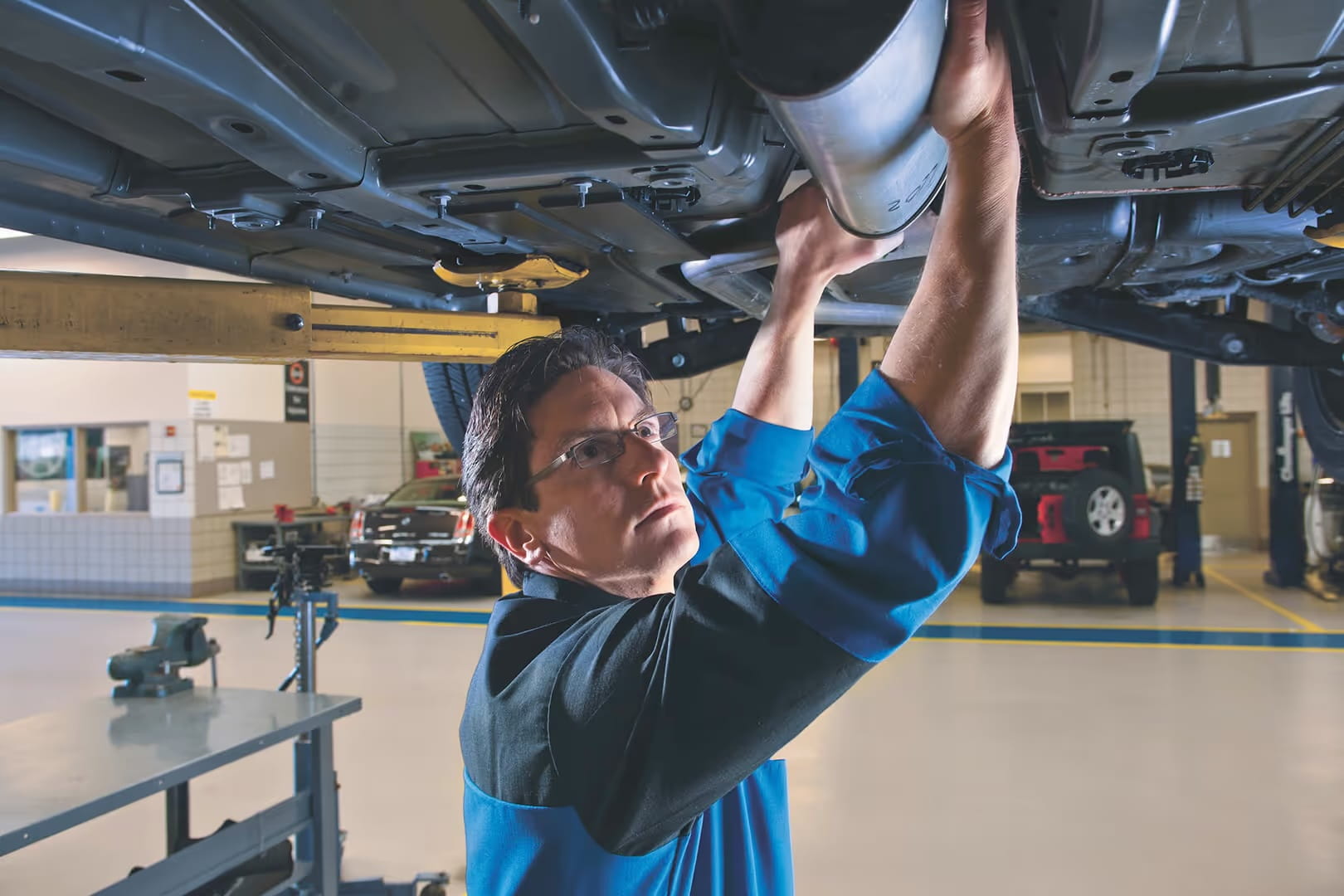 Service technician inspecting a RAM truck undercarriage and driveline