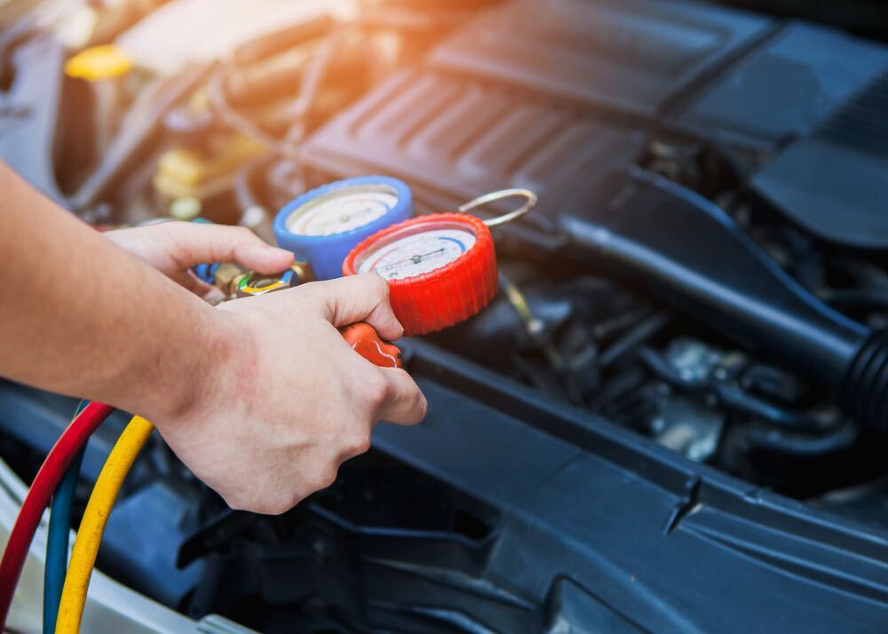 Technician servicing a vehicle air conditioning system